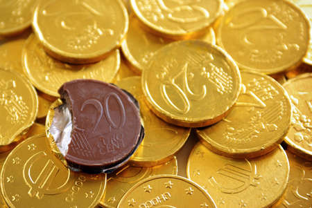 Pile of chocolate coins wrapped in shiny golden tinfoilの写真素材