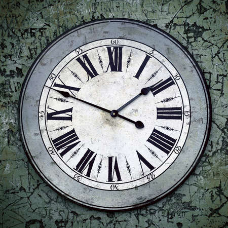 Old wall clock with roman numerals over a carved and scratched wall