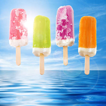 Four refreshing and colorful ice creams against a blue sky and sea の写真素材