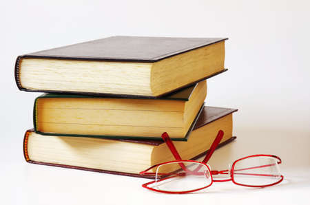 pile of three books and a pair of glasses isolated in whiteの写真素材