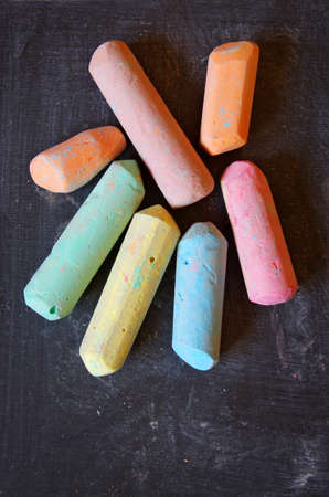 Dirty and used blackboard and pieces of colored chalk