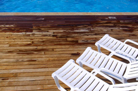 Top view of two empty white deck chairs in a swimming pool
