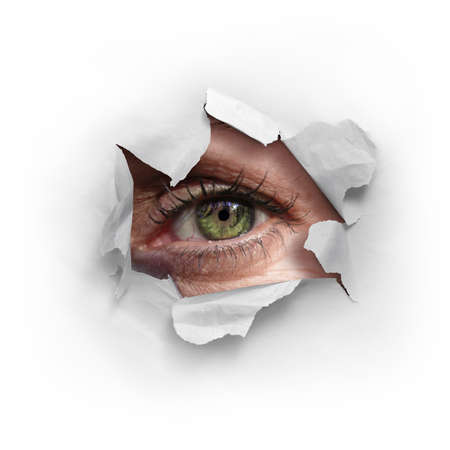 Female green eye looking through a ripped hole in a white paper
