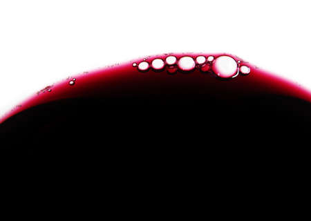 Close-up of red wine bubbles in a transparent glass