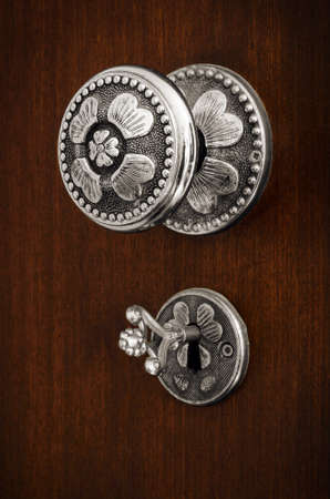 Old silver Doorknob and key on a brown wooden doorの写真素材