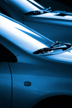 Black and blue image with the detail of two cars windshield wipers lit by low sunlight の写真素材