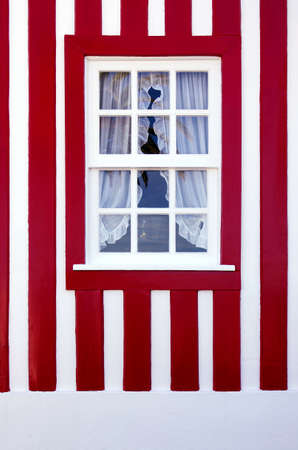 Single window on a red and white striped wall of a typical house in Costa-Nova, Aveiro, Portugal.