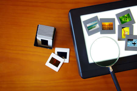 Top view of a lightbox with color slides and a magnifier lens over a wooden table