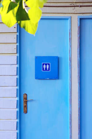 Blue painted wooden door of a unisex water-closet facilityの写真素材