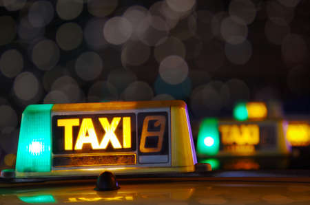 Row of taxi signs from parked taxis in a city street at nightの写真素材