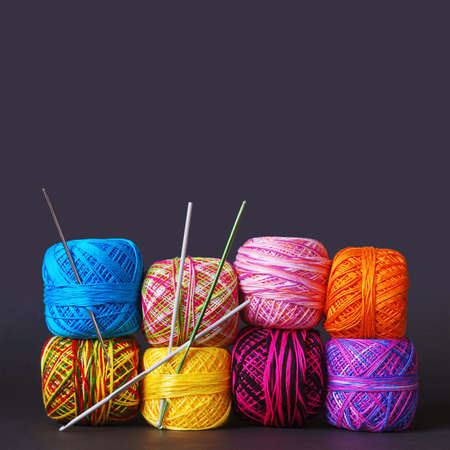A stack of colorful yarn coils and needles over grey backgroundの写真素材