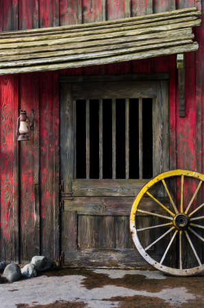 Detail of old wagon wheel next to a wooden wild west typical houseの写真素材