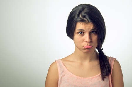 Portrait of a teenager brunette girl with pouting sad expression