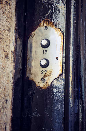Two vintage doorbell buttons in the door of an old buildingの写真素材