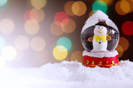 Snow globe with snowman over christmas lights backgroundの写真素材