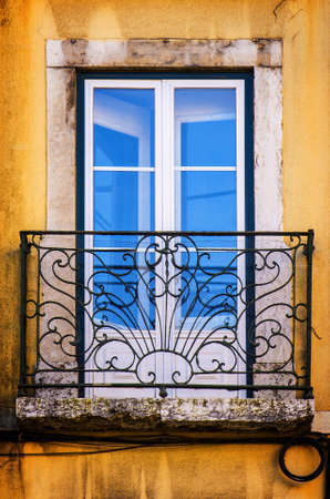Old and damaged window with iron balcony in a yellow wallのeditorial素材