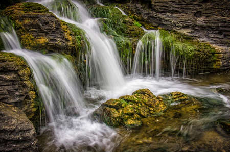 Beautiful motion blurred waterfall flowing from mossy rocks