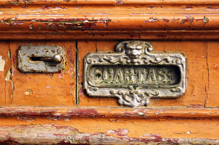 Old mailbox slot in an old wooden door painted orangeの写真素材