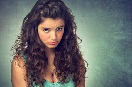 Portrait of a teenager brunette girl with pouting sad expression