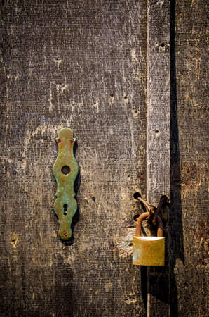 Detail of a old scratched wooden door with rusty padlock