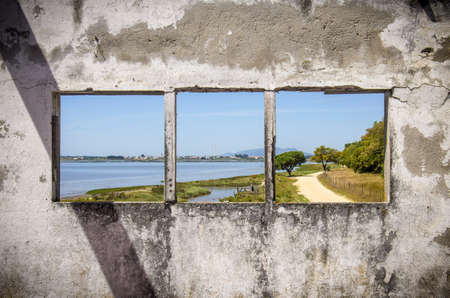 Row of three windows in a damaged white wall showing a landscapeの写真素材