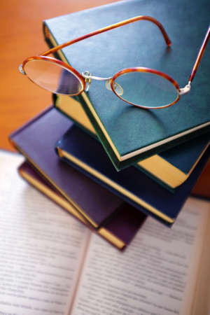 Pile of old books and a pair of vintage glasses on topの写真素材