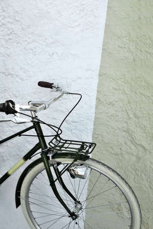 Detail of a vintage green and yellow bicycle against a wallの写真素材
