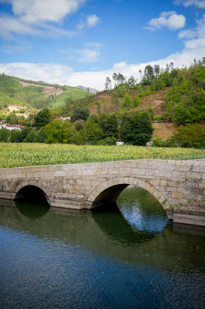 Remote rural landscape with a river and old romanic bridgeの写真素材