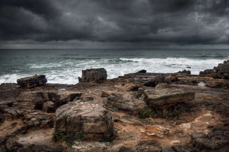 Stormy seascape with rocks in the foreground and dramatic cloudy sky