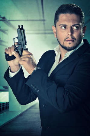 Male agent in an alert position and loading the chamber of his handgun