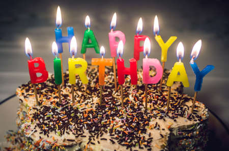 Top of cake with colorful letter shaped candles saying Happy Birthdayの写真素材