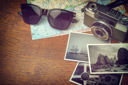 Vintage camera, map, sunglasses and photo prints on wooden table with copy spaceの写真素材