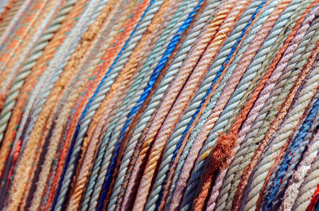 Background of aligned colorful old fishing ropes under sunlight