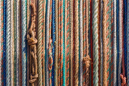 Background of aligned colorful old fishing ropes under sunlight