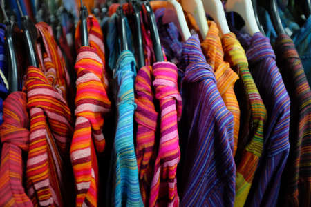 Colorful shirts hanged in a rack for sale in a marketの写真素材