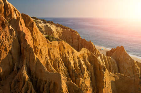 Sharp and steep cliffs near a beach under sunset warm lightの写真素材