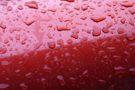 Water drops background with reflected light on the roof of a red carの写真素材