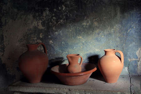 Still live with ancient pottery items in a stone counter and lit by a windowの写真素材