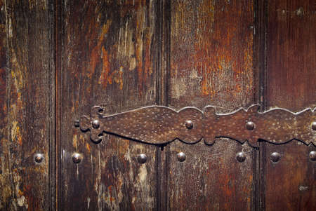 Detail of a rusty old iron hinge on a wooden doorの写真素材