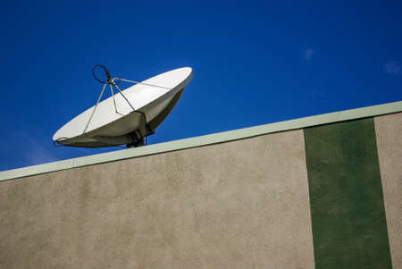 A disc antenna on the roof of a building capturing satellite signalの写真素材