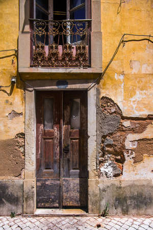 Facade of a ruined yellow house with brown door and window