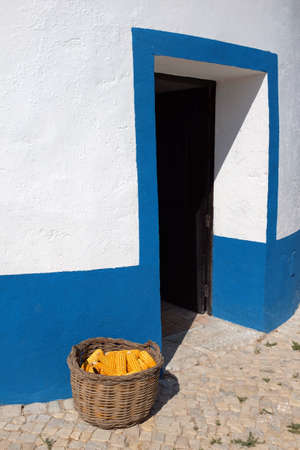 Detail od the entrance of a typical Portuguese windmill with a basket full of corn cobsの写真素材