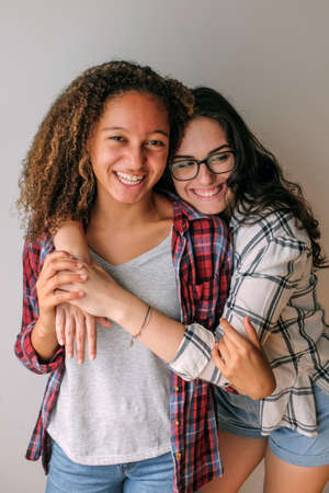 Two teenage best friends girls hugging and smiling in a photoshootの写真素材