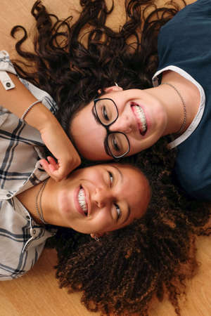 Two teenage best friend girls lying in the ground cheek to cheek