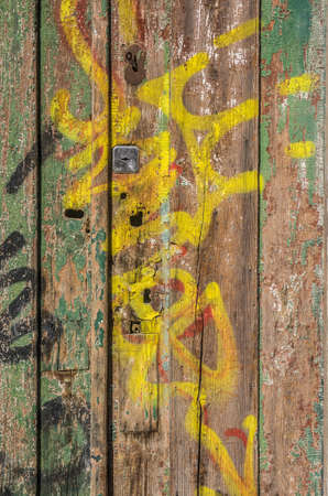 Demaged old wooden door with peeling paint and graffitiの写真素材