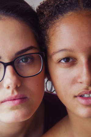 Portraits of two happy girls best friends with half faces cheek to cheekの写真素材