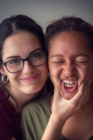 Portraits of two playful girls best friends with faces cheek to cheekの写真素材