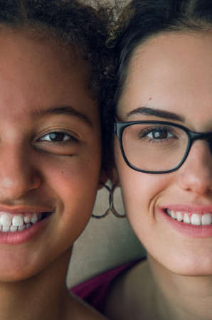 Portraits of two happy girls best friends with half faces cheek to cheekの写真素材