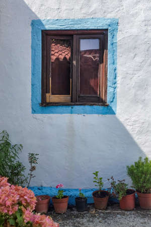 Rural house facade with windoe and old vases of flowersの写真素材