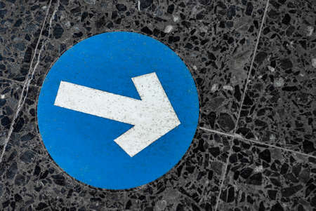 Blue round traffic road sign with white arrow symbol pointing rightの写真素材